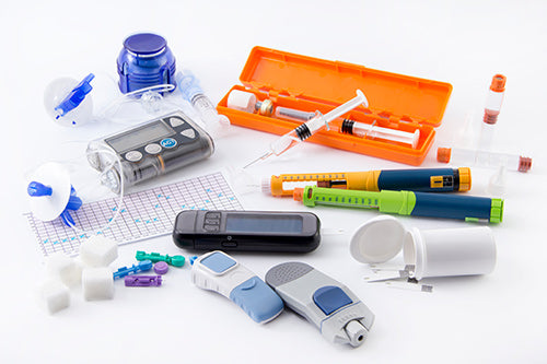 Assorted diabetes supllies including insulin needles, blood testing devices, and vials. 